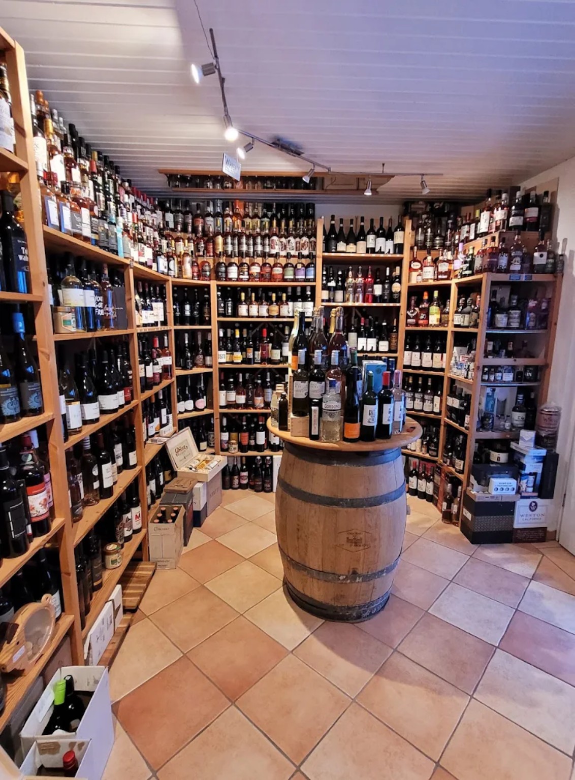 Blick in den Weinhandel Trompeter mit dicht gefüllten Regalen und einem Fass als Präsentationstisch