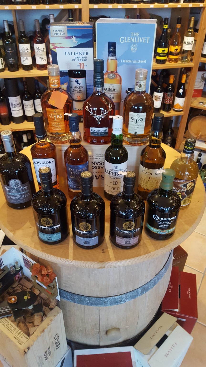 Eine Auswahl verschiedener Whiskys auf einem Fass im Geschäft